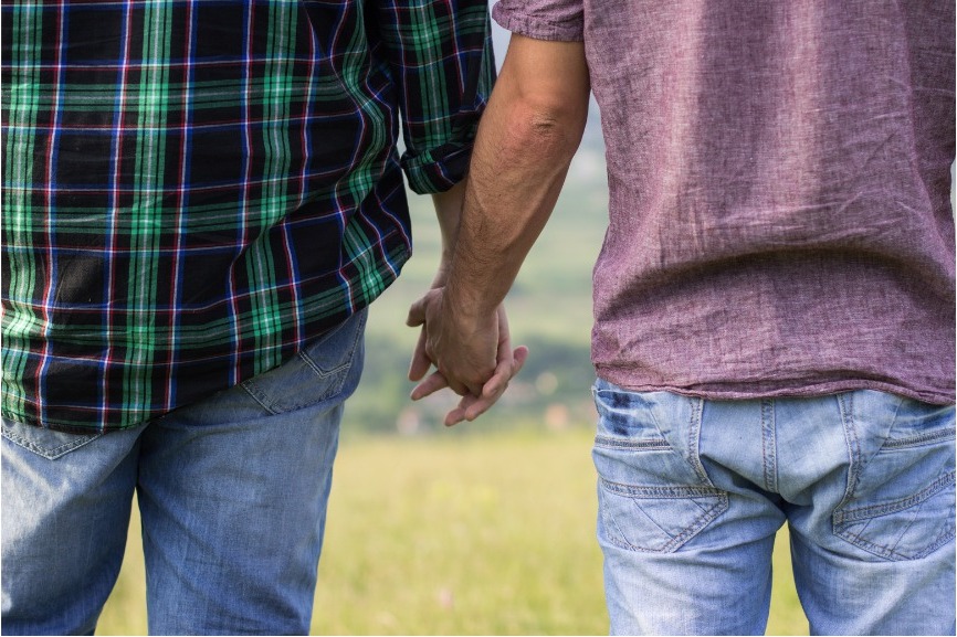 Two men resting close in tender intimacy, soft natural light