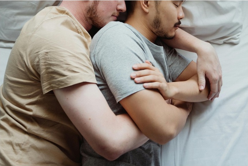 Two men smiling, arms around one another outdoors